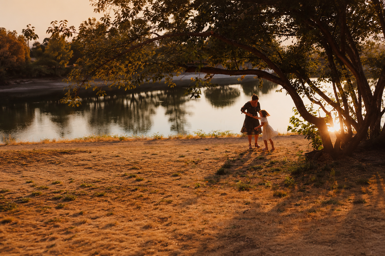 A mother and daughter dance by the river at golden hour